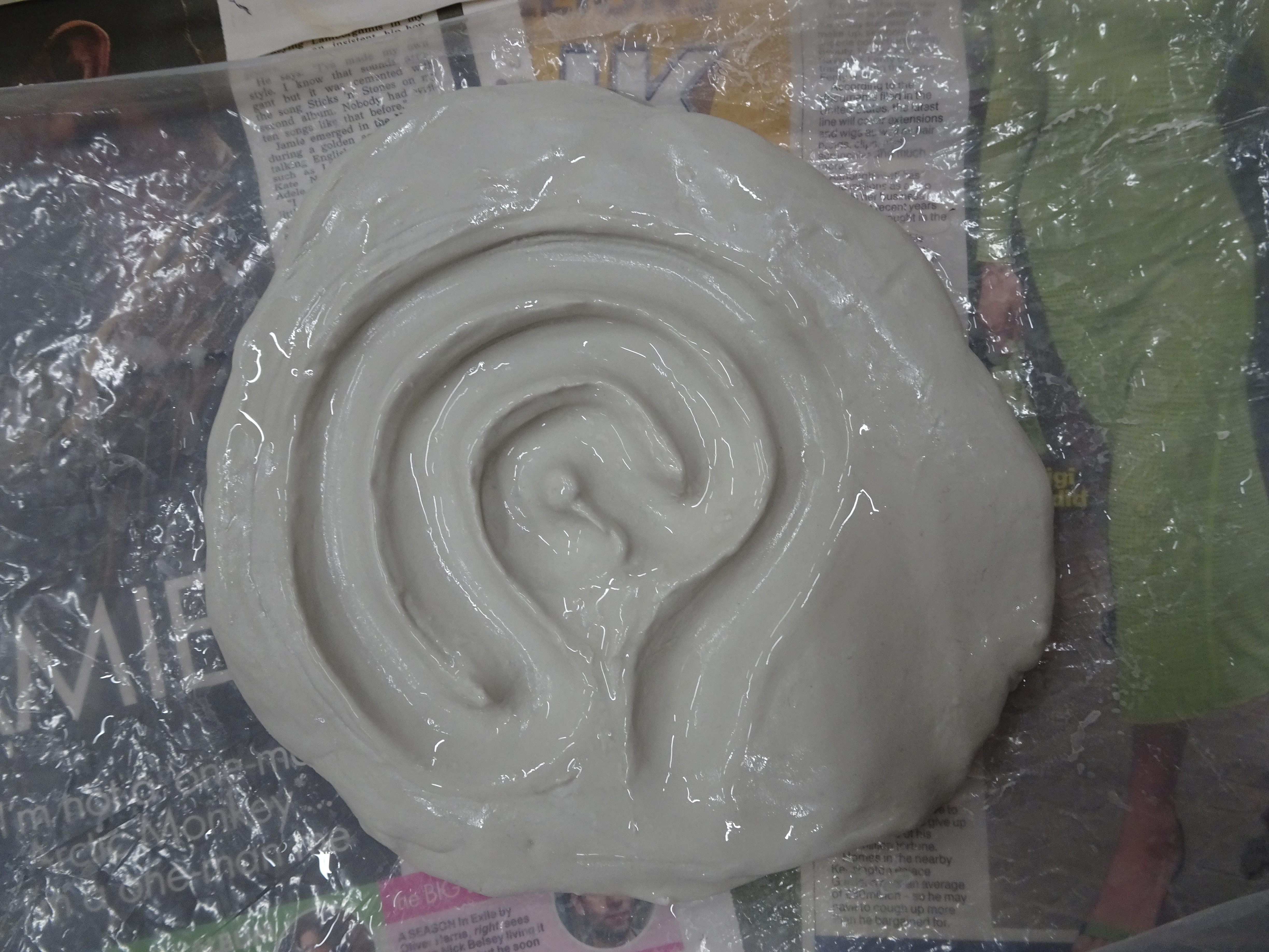 A finished four-course labyrinth in clay, still wet and resting on plastic and newspaper