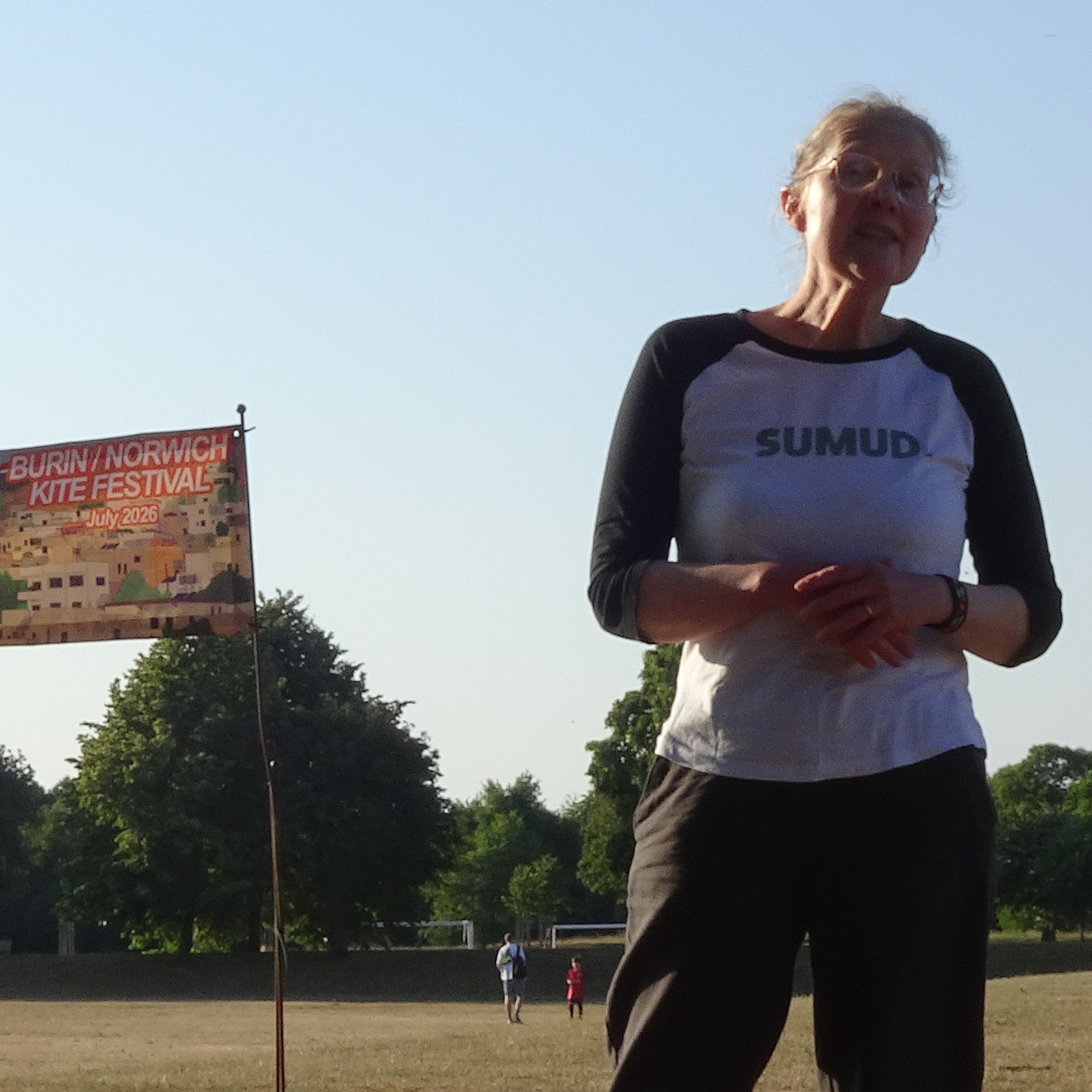 Reverend Fiona Haworth speaking in front of the Burin/Norwich Kite Festival banner.