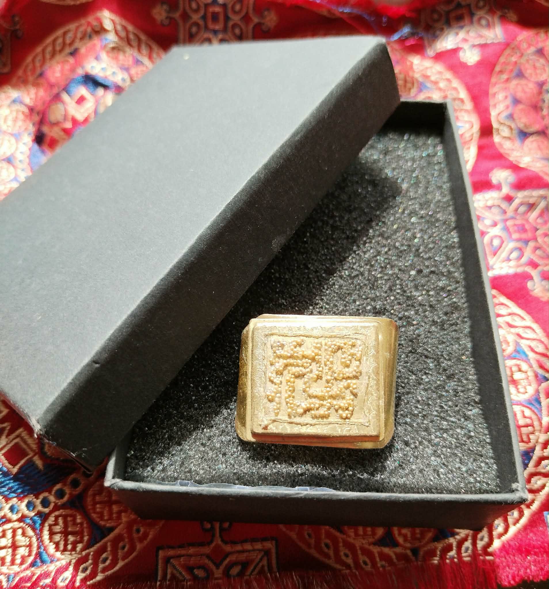 Image showing a square brass ring in a box. Picture by Taliesin Smith.